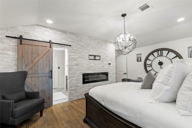 bedroom featuring a fireplace, lofted ceiling, dark hardwood / wood-style flooring, a barn door, and an inviting chandelier