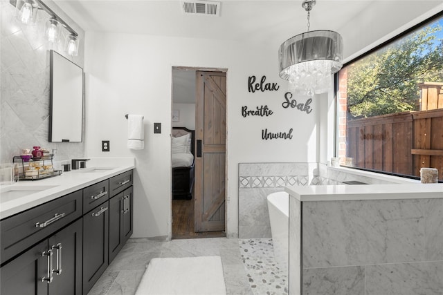 bathroom featuring vanity, a tub to relax in, and an inviting chandelier