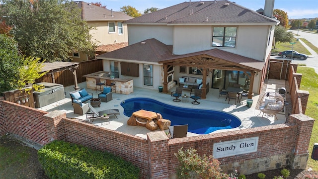 view of swimming pool featuring exterior kitchen, a patio, an outdoor fire pit, and a bar