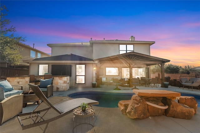 back house at dusk with a fenced in pool, an outdoor bar, and a patio area