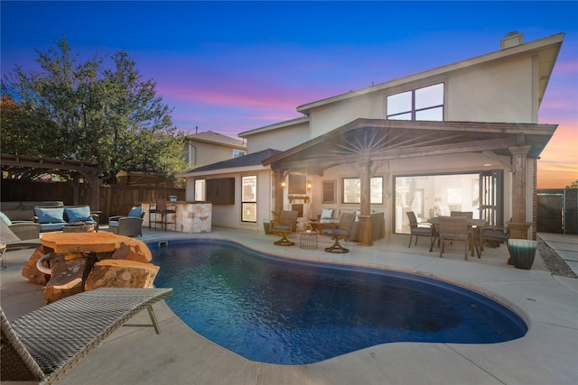 pool at dusk with a bar, an outdoor living space, and a patio