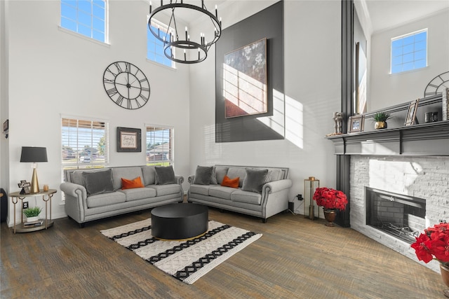 living room featuring dark hardwood / wood-style floors, a stone fireplace, a chandelier, and a high ceiling