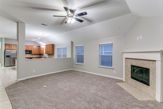 unfurnished living room featuring ceiling fan, light colored carpet, a fireplace, and vaulted ceiling