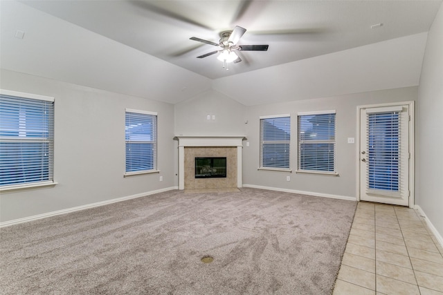 unfurnished living room with light tile patterned flooring, ceiling fan, a fireplace, and vaulted ceiling