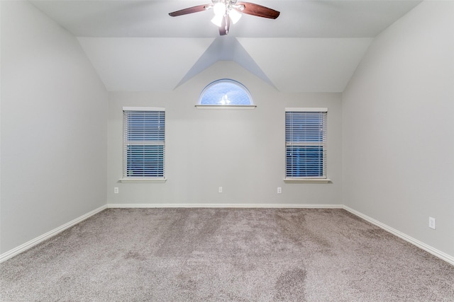 carpeted spare room featuring vaulted ceiling and ceiling fan