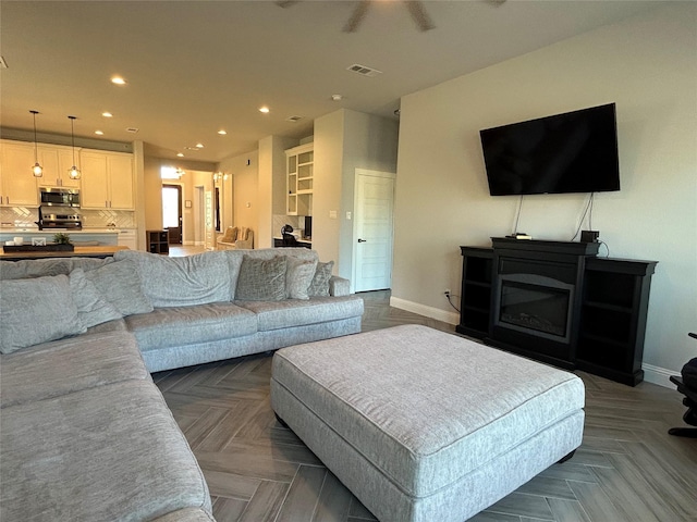 living room featuring ceiling fan and parquet flooring