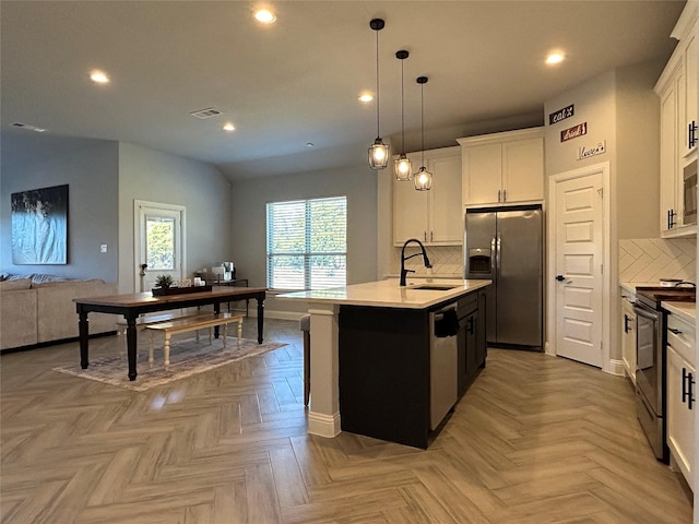 kitchen with white cabinets, light parquet flooring, stainless steel appliances, and a kitchen island with sink