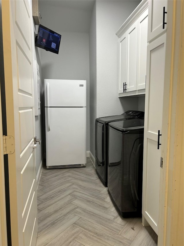 clothes washing area featuring cabinets, light parquet floors, and washer and clothes dryer