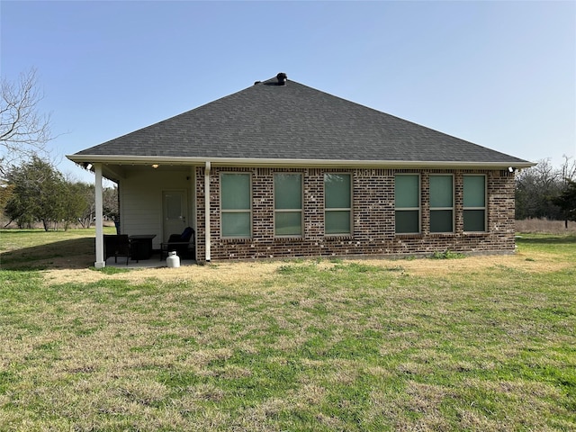 rear view of property with a patio area, a lawn, brick siding, and a shingled roof