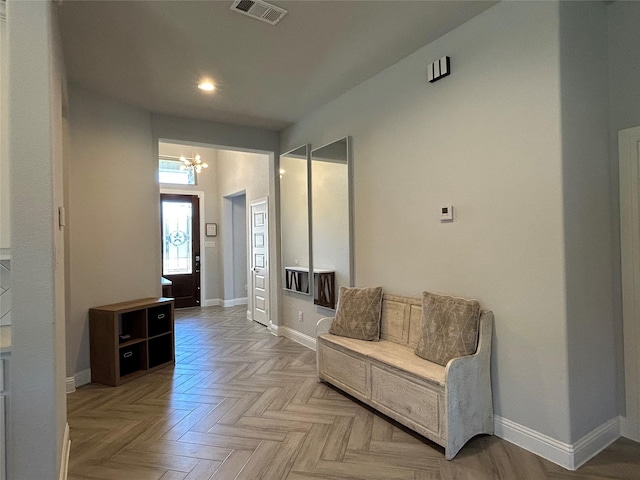 hall featuring an inviting chandelier, baseboards, and visible vents