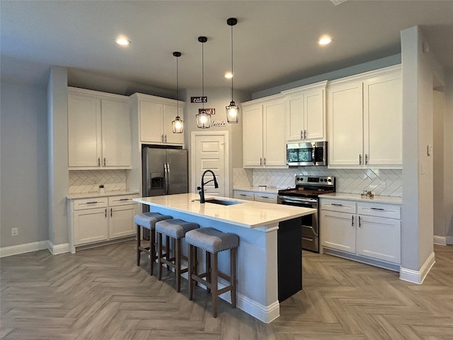 kitchen with sink, pendant lighting, a center island with sink, white cabinets, and appliances with stainless steel finishes