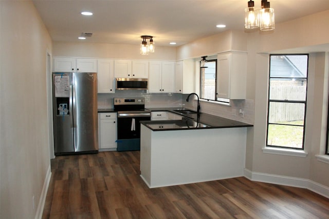 kitchen with white cabinetry, sink, kitchen peninsula, decorative light fixtures, and appliances with stainless steel finishes