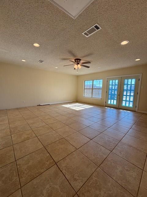 empty room with ceiling fan, light tile patterned floors, and a textured ceiling