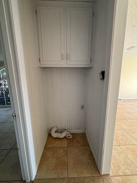 laundry room with electric dryer hookup, light tile patterned floors, and cabinets