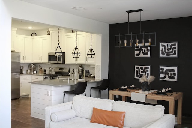 kitchen featuring appliances with stainless steel finishes, pendant lighting, tasteful backsplash, white cabinetry, and kitchen peninsula