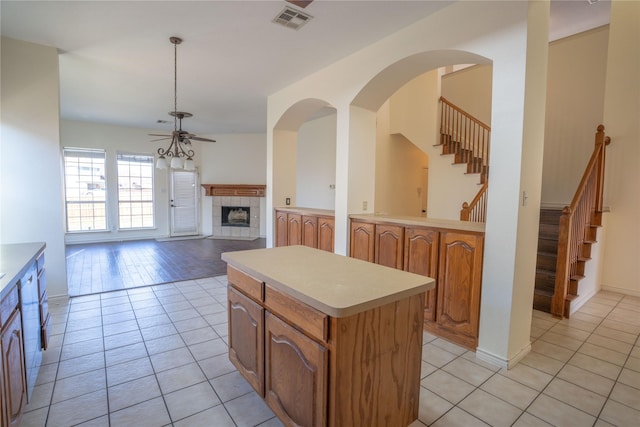 kitchen featuring pendant lighting, light tile patterned flooring, ceiling fan, a fireplace, and a kitchen island