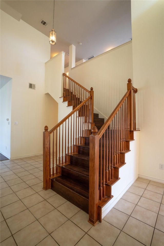 stairs featuring tile patterned flooring and a towering ceiling