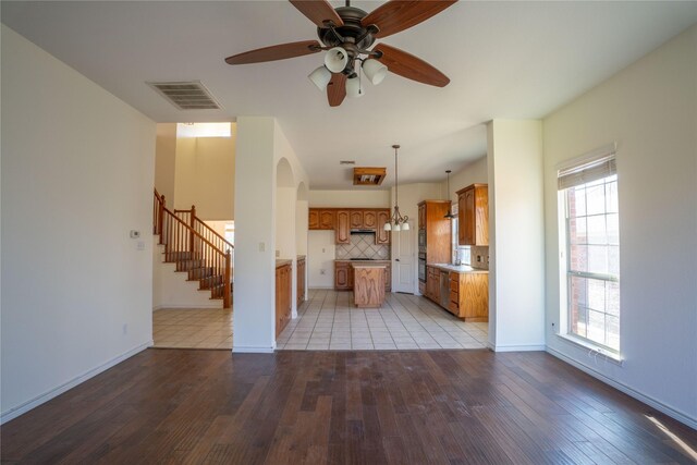 unfurnished living room featuring ceiling fan with notable chandelier and light hardwood / wood-style floors