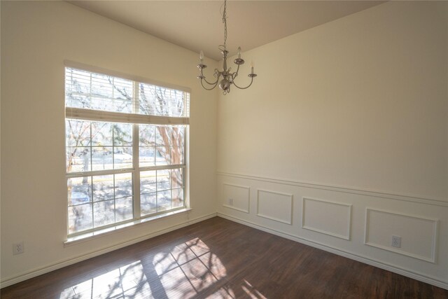 spare room with dark wood-type flooring and a notable chandelier