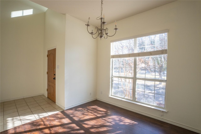 tiled spare room featuring a wealth of natural light and an inviting chandelier