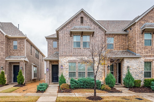 townhome / multi-family property with brick siding and roof with shingles