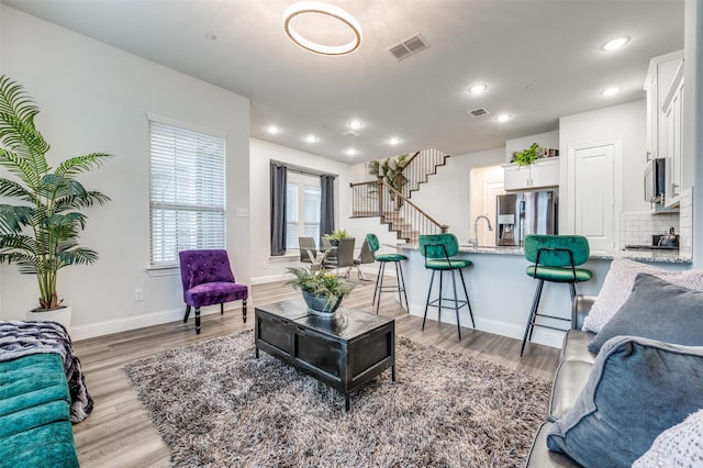 living room with light hardwood / wood-style floors and sink