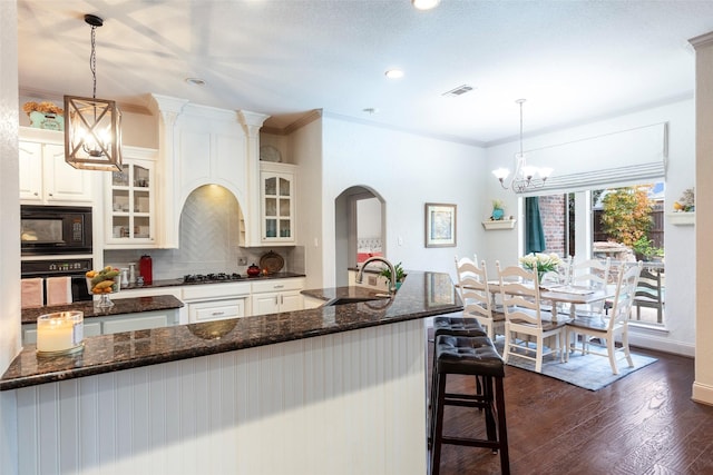 kitchen with tasteful backsplash, sink, black appliances, and decorative light fixtures