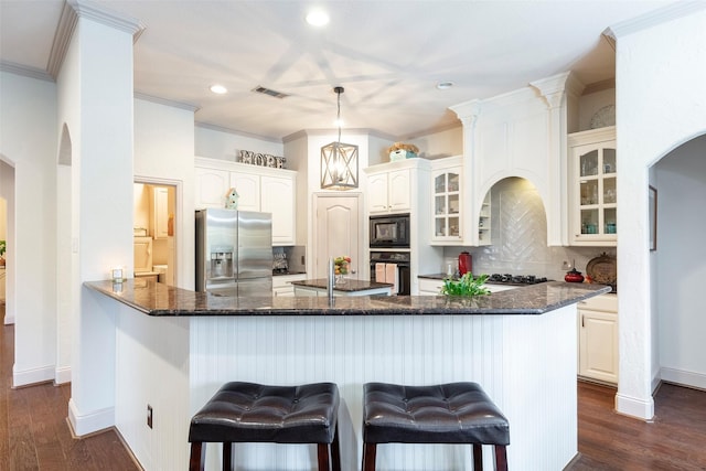 kitchen with black appliances, kitchen peninsula, tasteful backsplash, white cabinetry, and a breakfast bar area