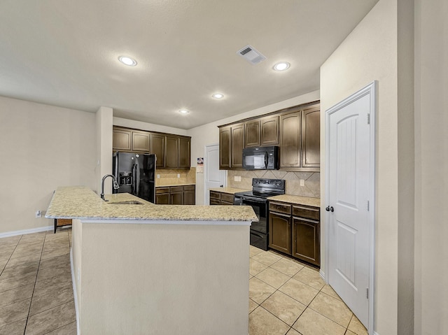 kitchen featuring dark brown cabinets, a center island with sink, light tile patterned floors, and black appliances