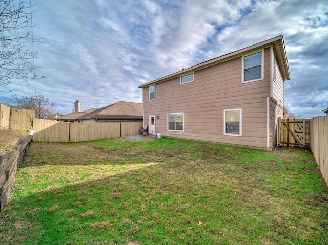 rear view of property with a fenced backyard and a yard