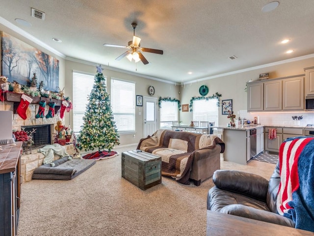 carpeted living room featuring ceiling fan, a stone fireplace, ornamental molding, and a textured ceiling