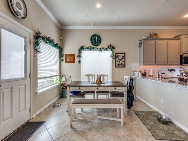 dining space with sink, ornamental molding, and light tile patterned flooring