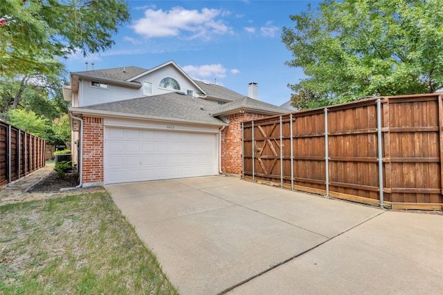 exterior space with a garage, driveway, brick siding, and fence