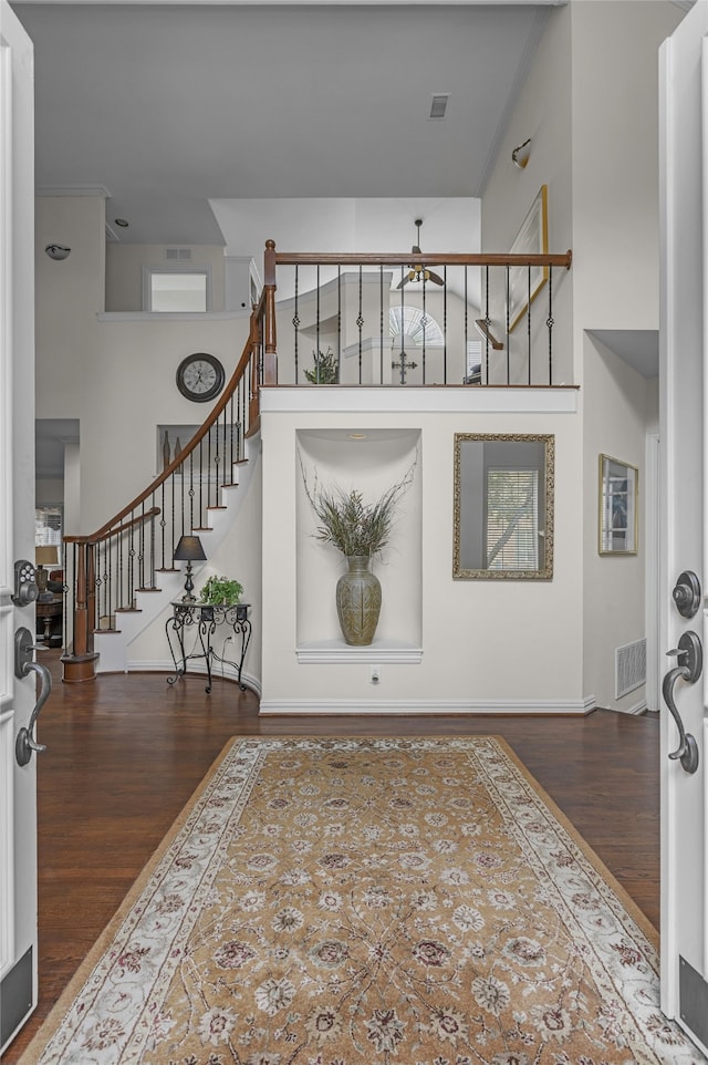 entryway featuring a high ceiling, stairs, visible vents, and wood finished floors