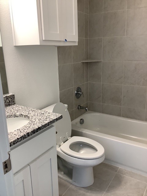 full bathroom with tile patterned floors, vanity, toilet, and tiled shower / bath combo