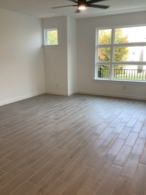 spare room featuring wood-type flooring, a wealth of natural light, and ceiling fan