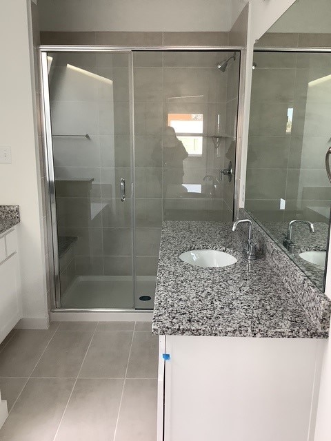 bathroom with tile patterned flooring, vanity, and an enclosed shower