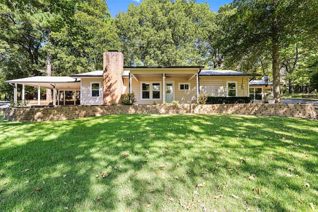 rear view of property with a lawn and a carport