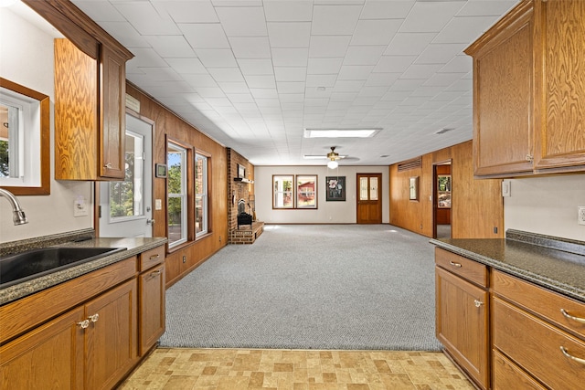 kitchen featuring ceiling fan, sink, light carpet, and wooden walls