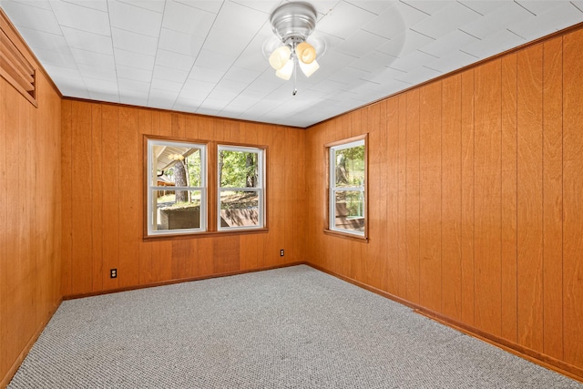 spare room with carpet floors, ceiling fan, and wood walls