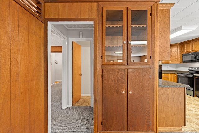 kitchen featuring range with electric cooktop, carpet, and wood walls