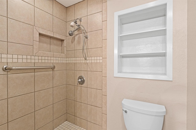 bathroom featuring a tile shower and toilet