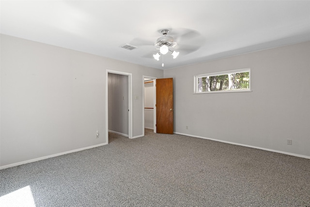 unfurnished bedroom featuring a spacious closet, a closet, ceiling fan, and carpet