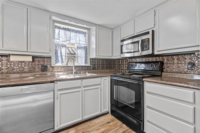 kitchen featuring light wood-type flooring, dishwashing machine, sink, white cabinets, and black range with electric stovetop