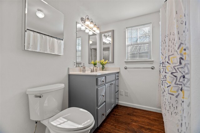 bathroom featuring hardwood / wood-style floors, vanity, toilet, and curtained shower