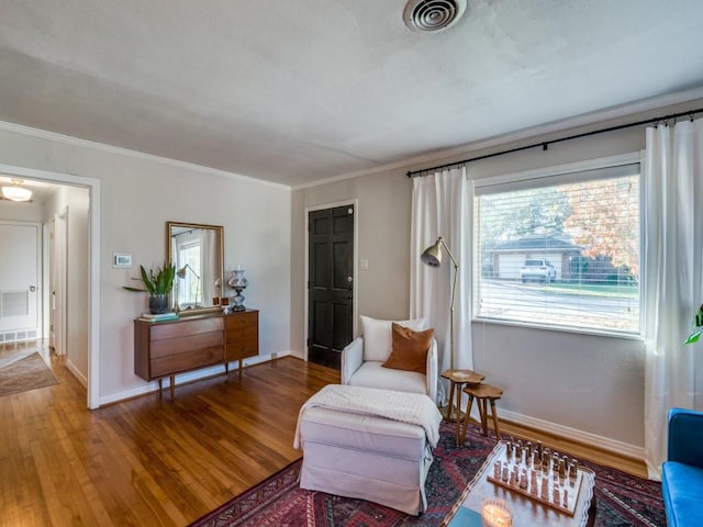 living area featuring wood-type flooring and crown molding