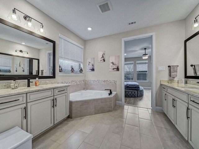 bathroom with tile patterned flooring, vanity, and a relaxing tiled tub