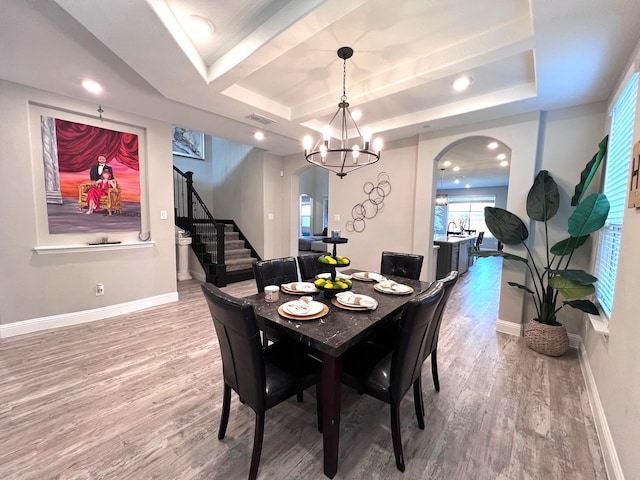 dining area with hardwood / wood-style floors, a tray ceiling, and a notable chandelier