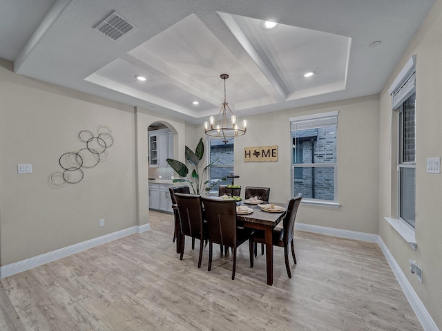 dining space with a healthy amount of sunlight, light hardwood / wood-style flooring, and a notable chandelier