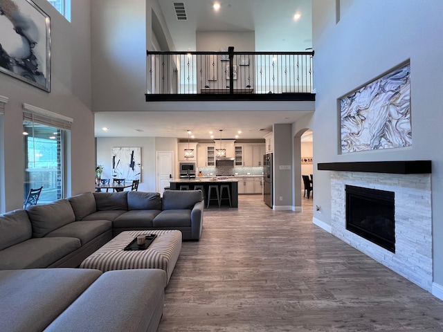 living room featuring plenty of natural light, a stone fireplace, and hardwood / wood-style floors